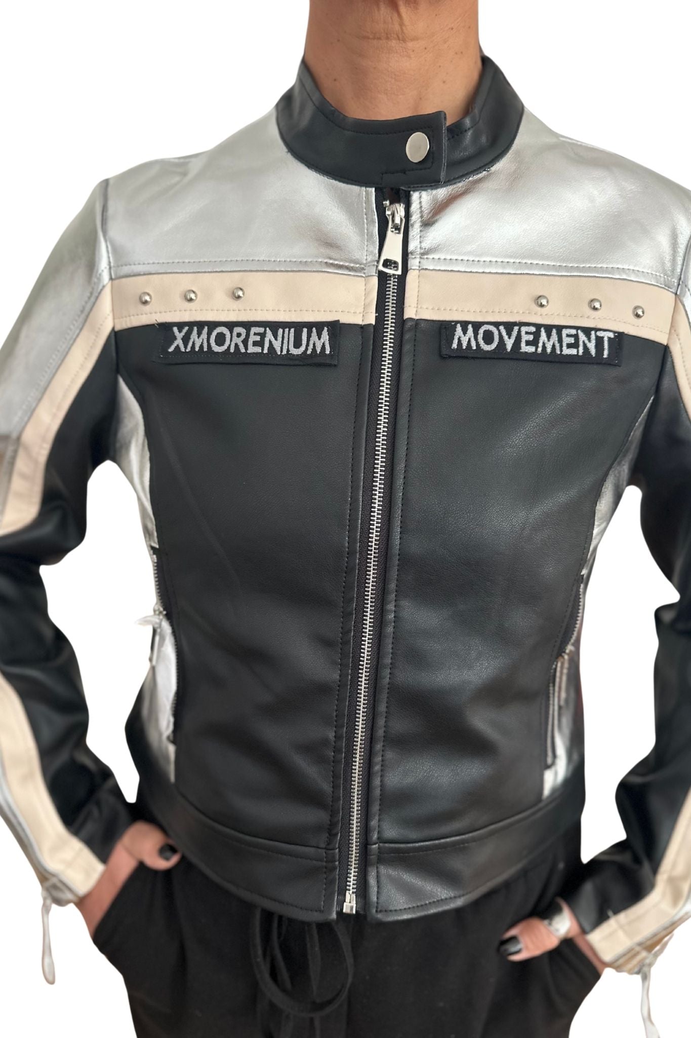 Person trägt silber-schwarze Kunstlederjacke mit Xmorenium- und Movement-Patches, beige Akzente und Reißverschlüsse sichtbar.